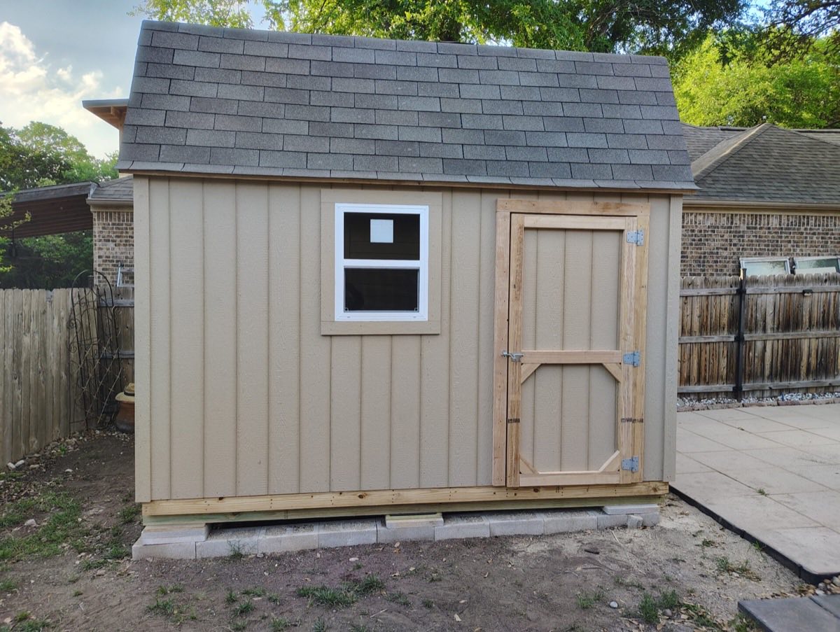 Small beige storage shed in yard