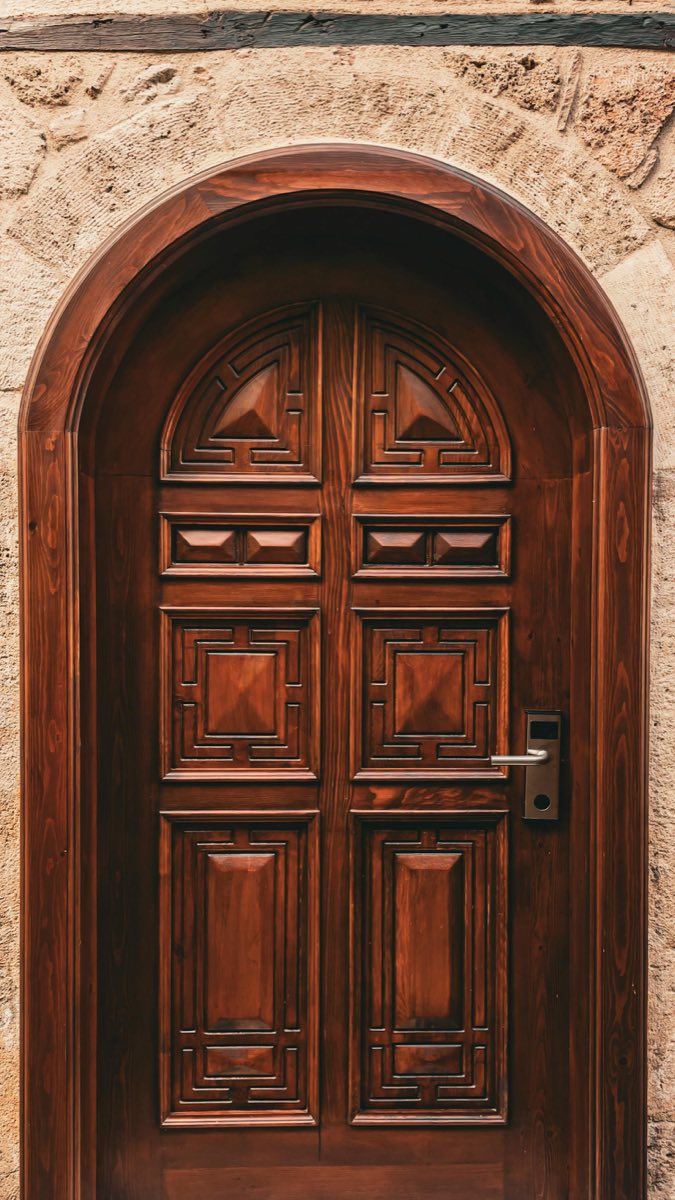 Arched wooden entry door in stone frame